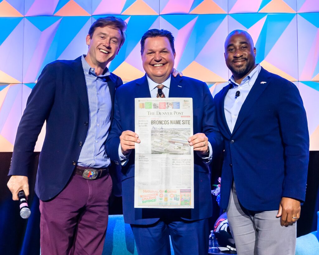 Denver Mayor Johnston, Chamber President J. J. Ament, and Broncos President Damani Leech hold paper celebrating Broncos news