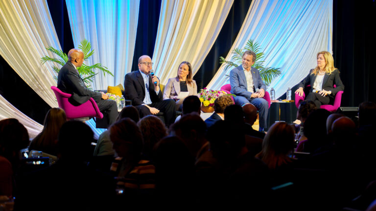 Business leaders Mowa Haile, Paige Goss, Todd Saliman, and Laura Hopkins sit with Colorado Governor Jared Polis on stage at the Denver Metro Chamber's State of the State event